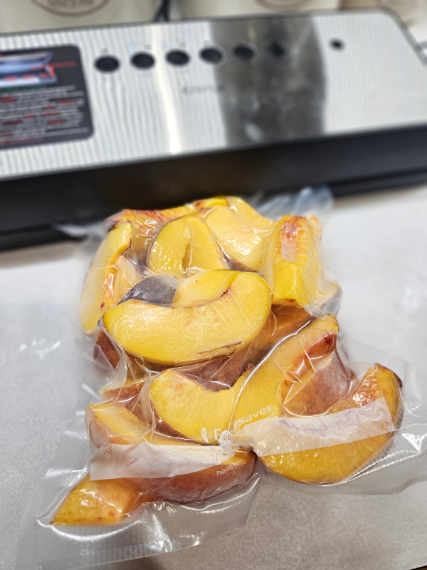 A bag of frozen peaches getting vacuum sealed
