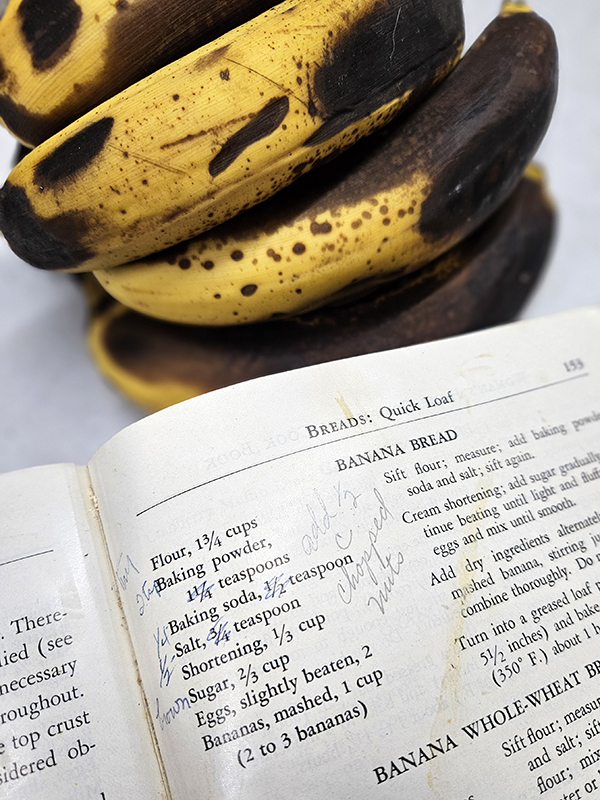 Grandma's Banana Bread recipe with stains and ripe bananas in the background
