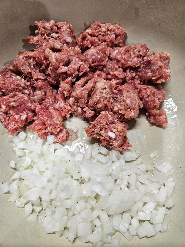Raw ground sausage and onions ready to be cooked.