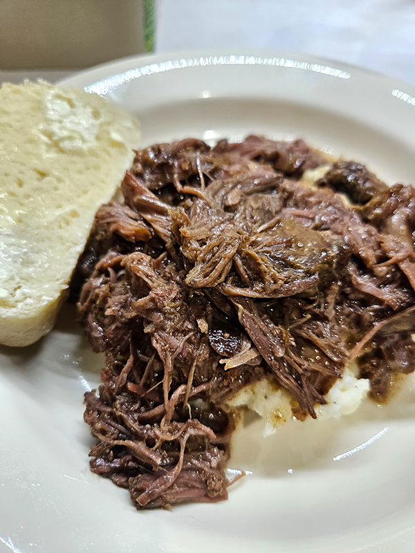 Mississippi pot roast on mashed potatoes with french bread on the side.