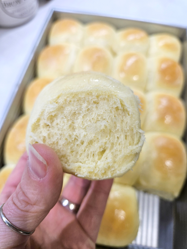A hand holding up an easy homemade dinner roll