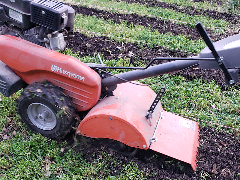 A Husqvarna tiller tilling up the soil in rows. Definitely not part of a no-till method!