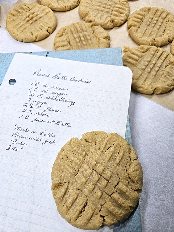 My grandma's recipe next to finished baked peanut butter cookies.