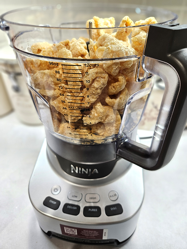 A food processor filled with pork rinds