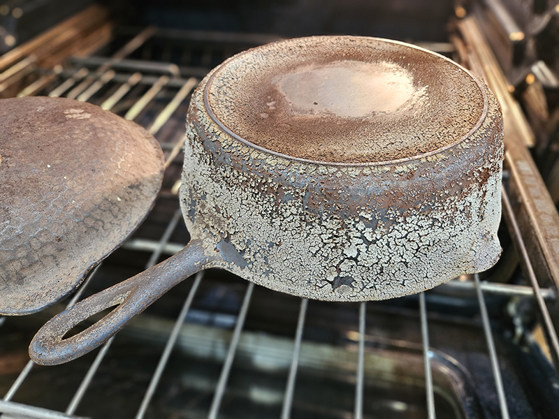 A cast iron skilled with dried seasoning and food bits on it.