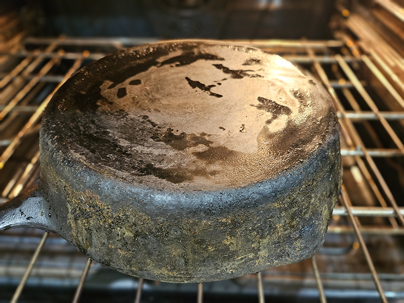 A very dirty cast iron skillet upside down in an oven.