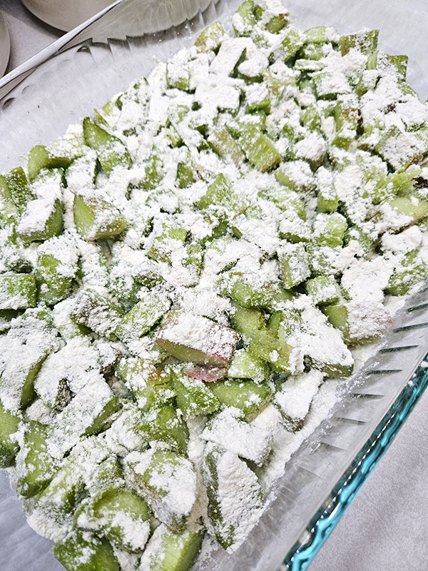 Chopped sugar and rhubarb with flour on top in a casserole dish