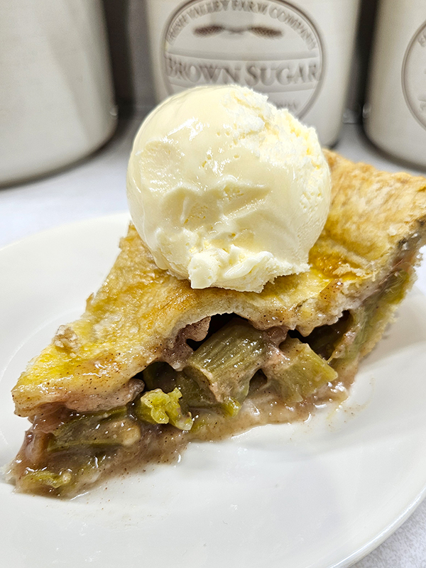 A slice of homemade rhubarb pie with ice cream on top