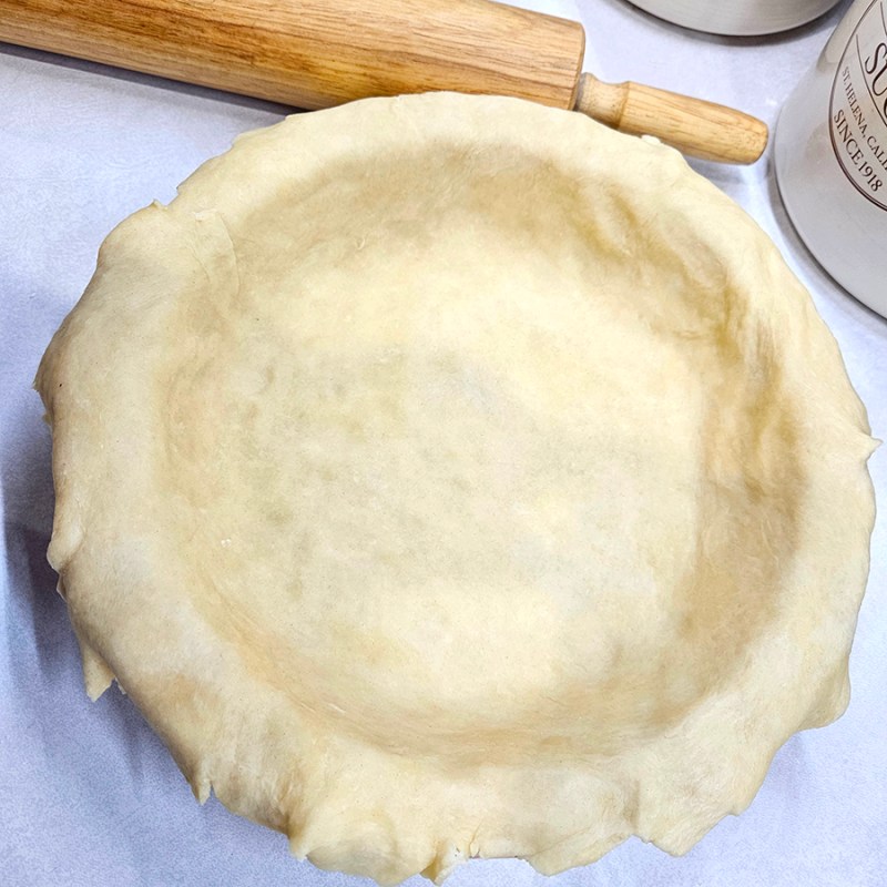Rustic Pie Crust in a pie plate with a rolling pin behind it.