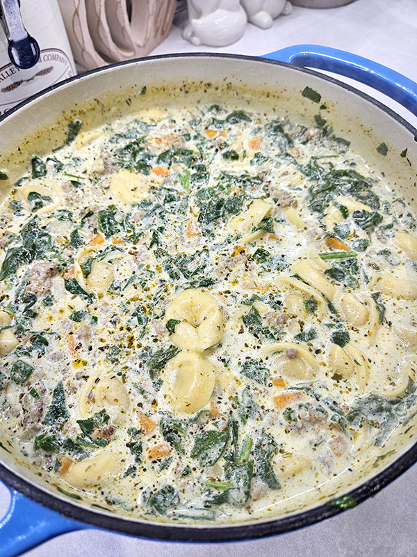 A dutch oven full of the sausage and cheese tortellini soup