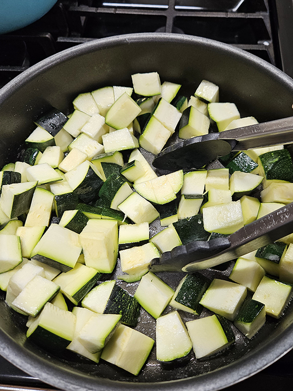 Mixing the zucchini to make sure they are all evenly coated in melted butter.