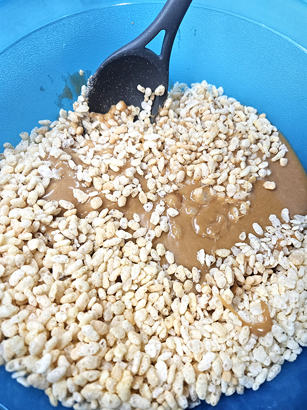 Mixing the cereal with the peanut butter mixture for my soft and chewy scotcheroos