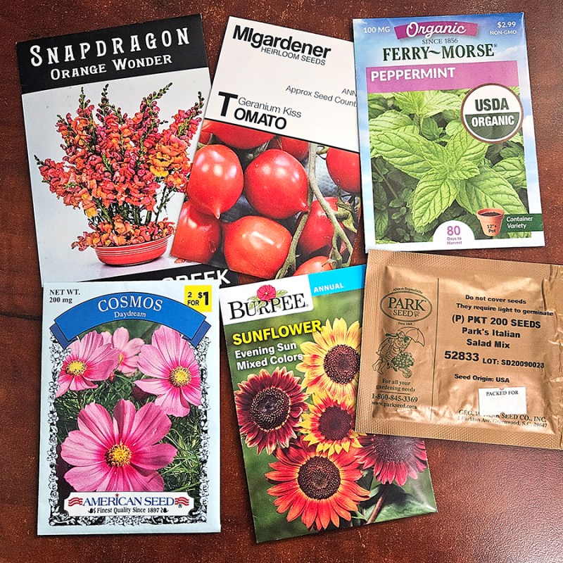 A pile of different company's seed packets with lots of information on them.