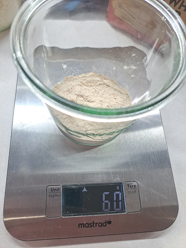 Flour inside of a jar that is sitting on a digital kitchen scale