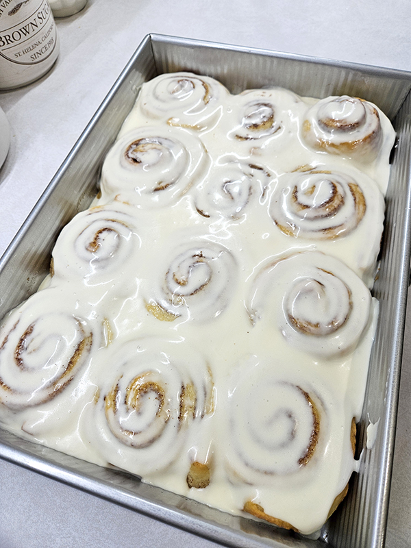 A pan of freshly baked and iced sweet icing cinnamon rolls