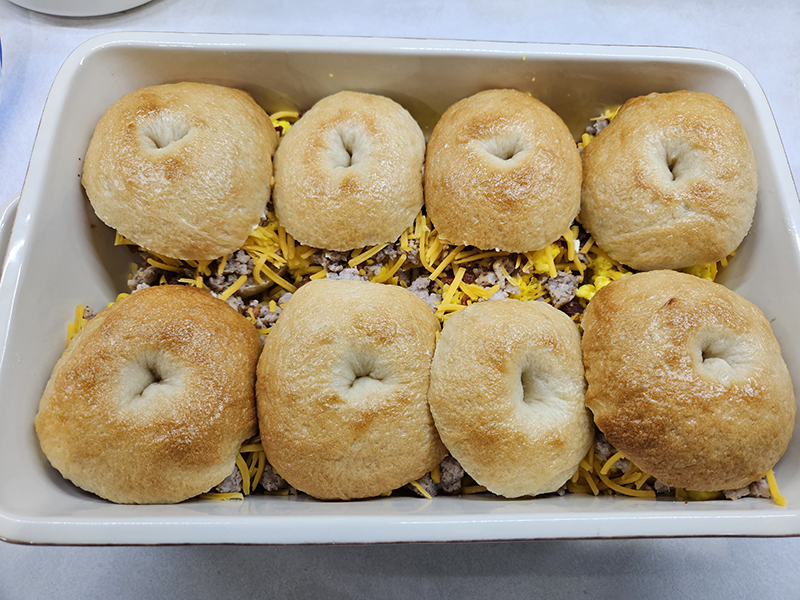 A dish of bagel breakfast sliders without seasoning on top. 