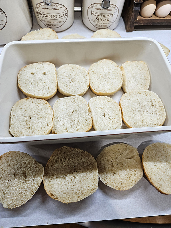 Bagel bottoms cut in a 9x13 dish with the tops outside the dish